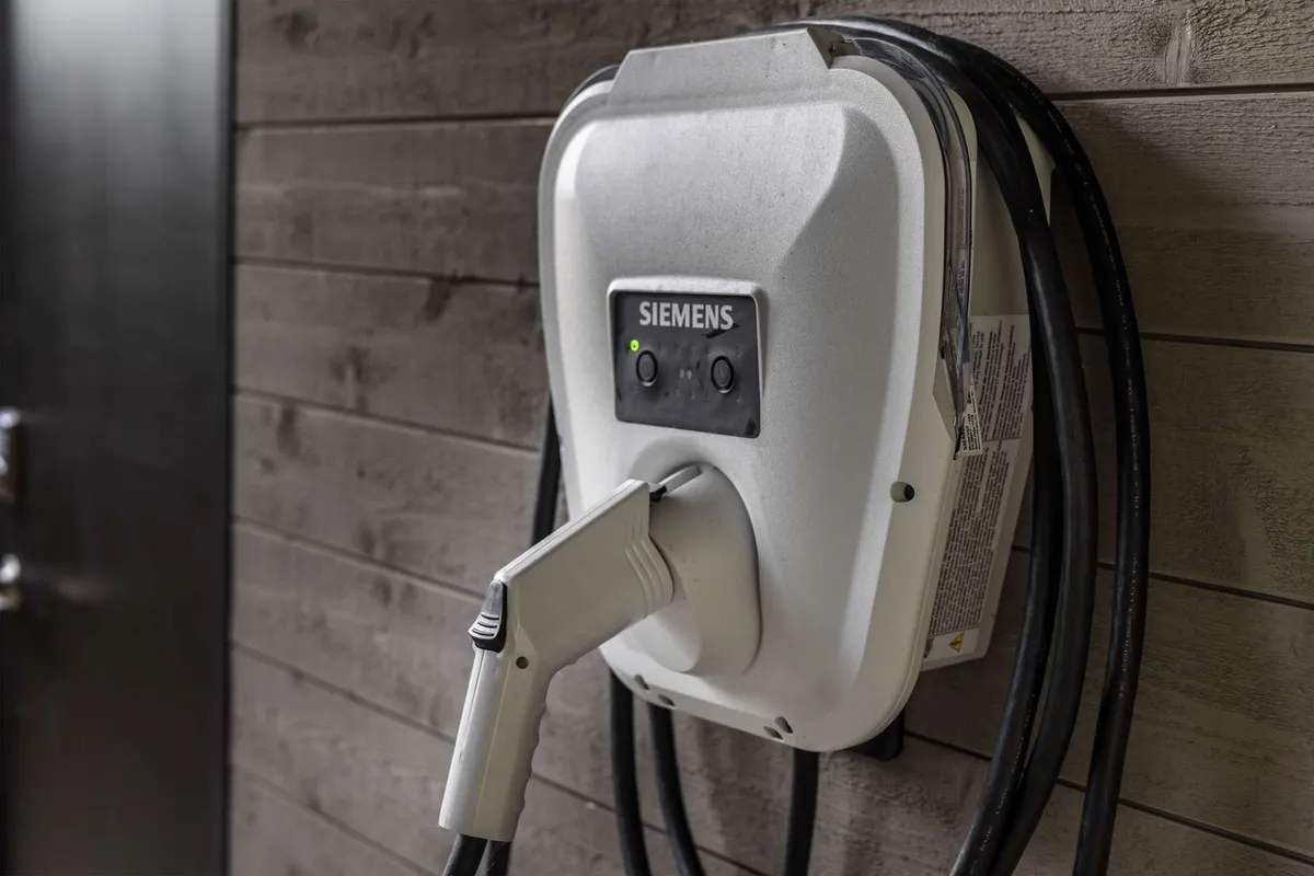 A close-up view of a dedicated electric vehicle charger mounted on a textured wall, reflecting an eco-conscious and tech-forward amenity available at the villa.