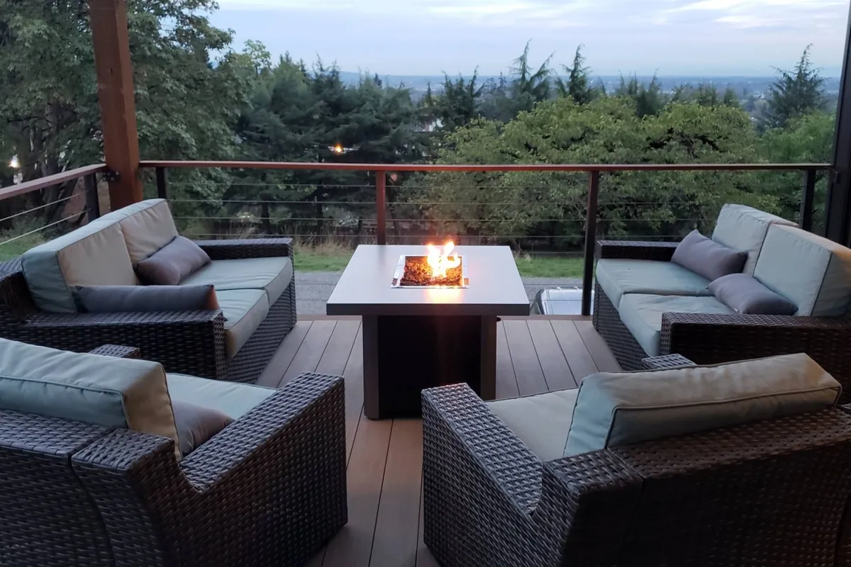 This image features an inviting outdoor fire pit area surrounded by comfortable seating and a backdrop of lush trees. The space is set up for relaxed outdoor gatherings, perfect for evening conversations and sharing s’mores under the sky.