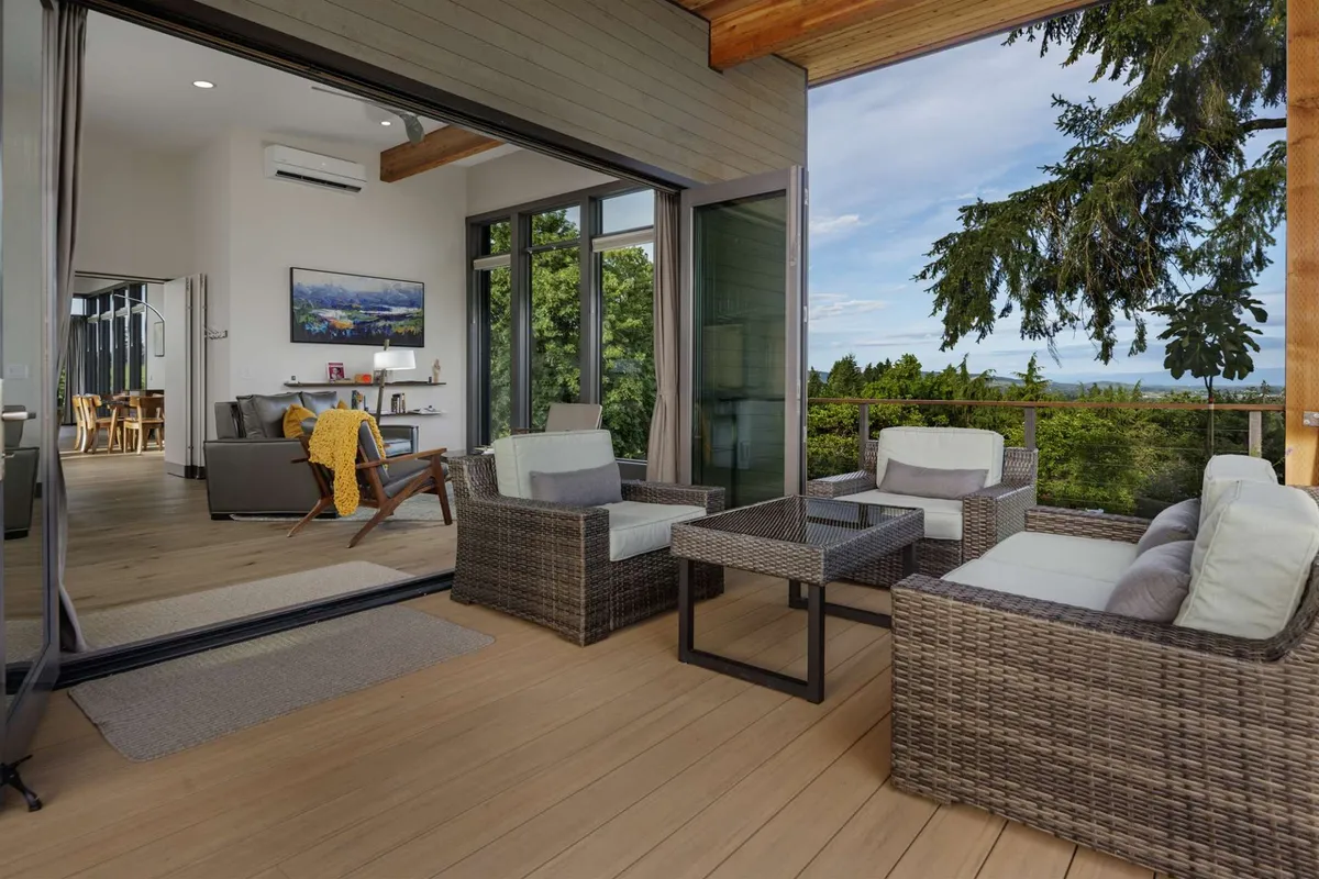 A comfortable seating area with large windows offering abundant natural light and views of greenery. The space is set for relaxation, with cozy furnishings and a tranquil mood.
